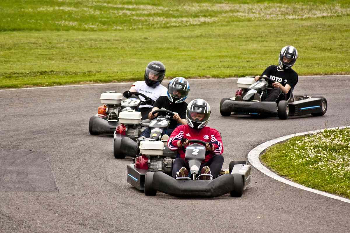 Quatre personnes en karting sur une piste avec un terrain gazonné à l'arrière-plan