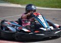 Un enfant pilote un kart de course sur piste, casque noir