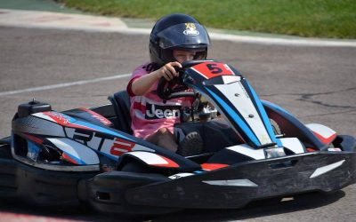 Un enfant pilote un kart de course sur piste, casque noir