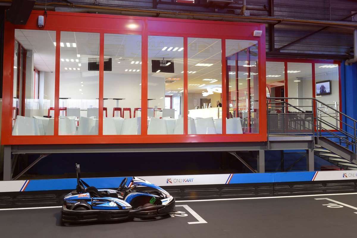 Un kart sur piste intérieure devant une salle vitrée