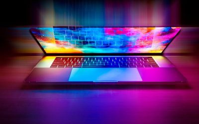 Un ordinateur portable ouvert projette des couleurs néon sur le bureau