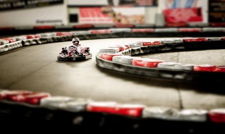 Un kart rouge avec pilote navigant un virage de circuit intérieur