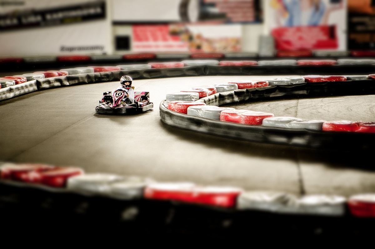 Un kart rouge avec pilote navigant un virage de circuit intérieur