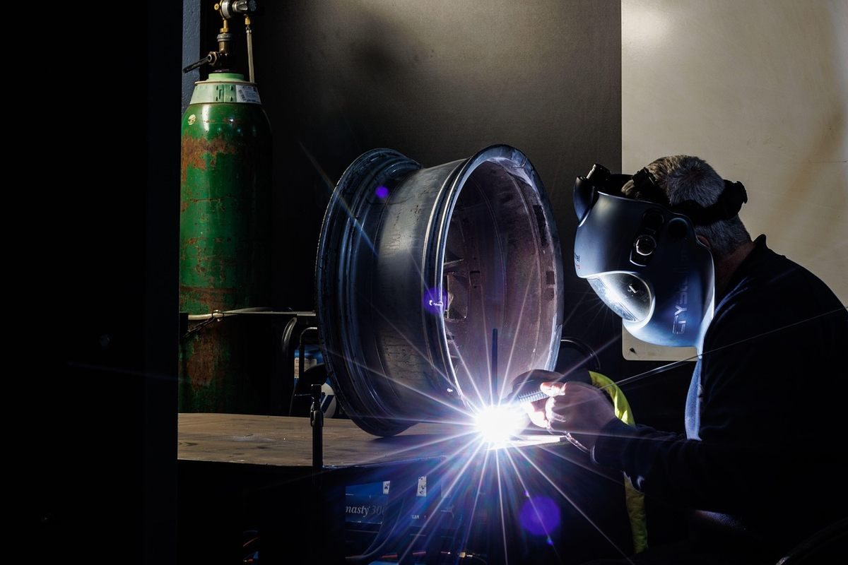 Un soudeur portant un casque protège un disque métallique en atelier