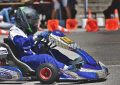 Un coureur en combinaison bleue pilote un kart de course sur circuit