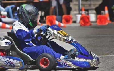 Un coureur en combinaison bleue pilote un kart de course sur circuit