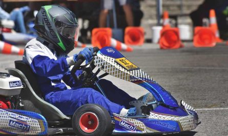 Un coureur en combinaison bleue pilote un kart de course sur circuit