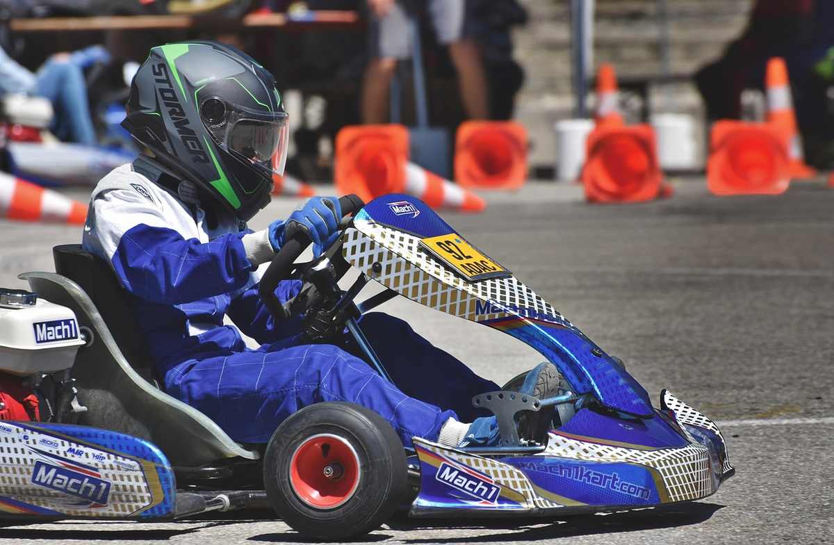 Un coureur en combinaison bleue pilote un kart de course sur circuit